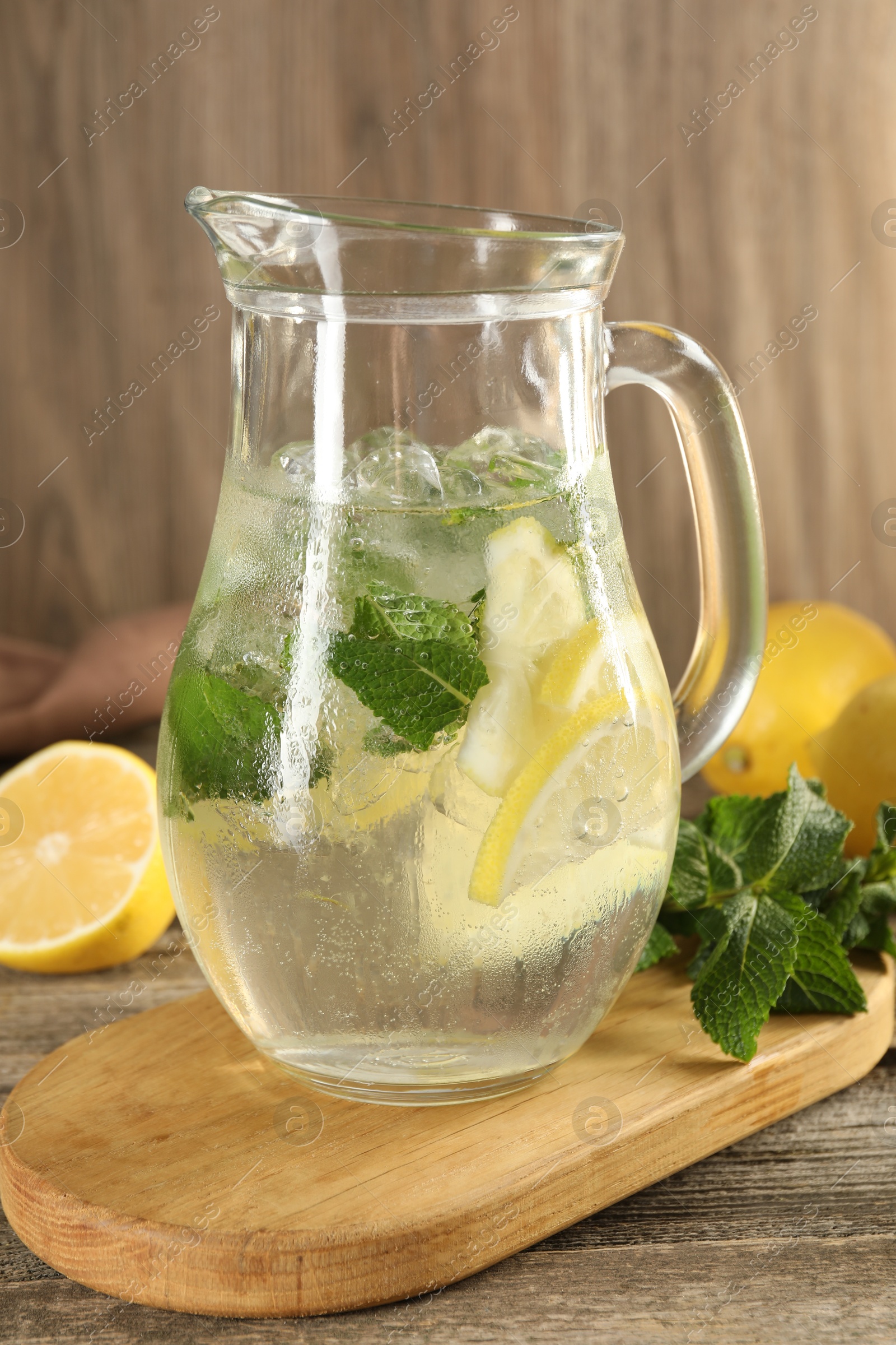 Photo of Refreshing lemonade with mint in jug on wooden table