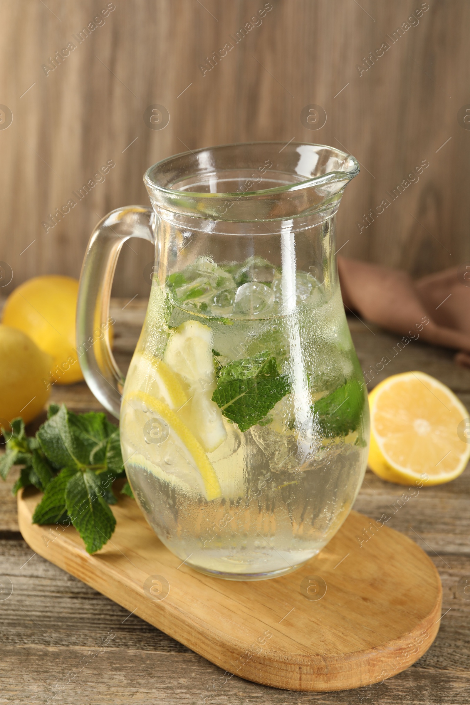 Photo of Refreshing lemonade with mint in jug on wooden table