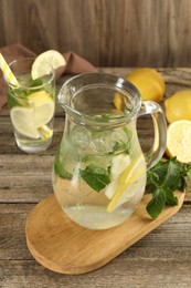 Refreshing lemonade with mint in jug and glass on wooden table