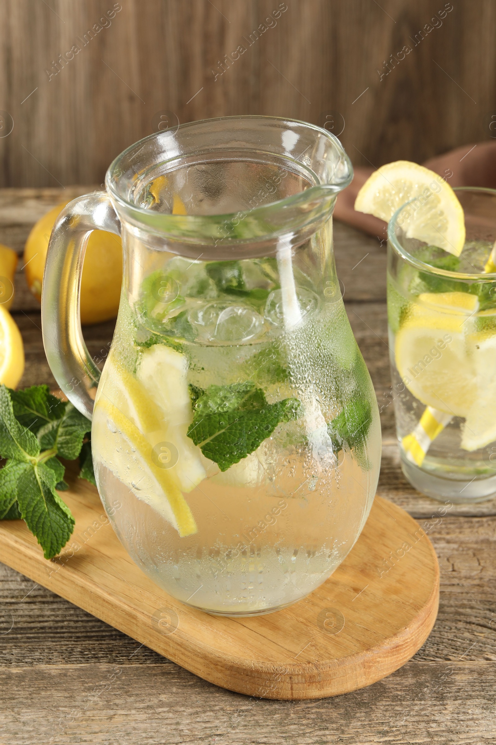 Photo of Refreshing lemonade with mint in jug and glass on wooden table