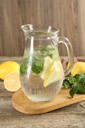 Photo of Refreshing lemonade with mint in jug on wooden table