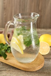 Refreshing lemonade with mint in jug on wooden table