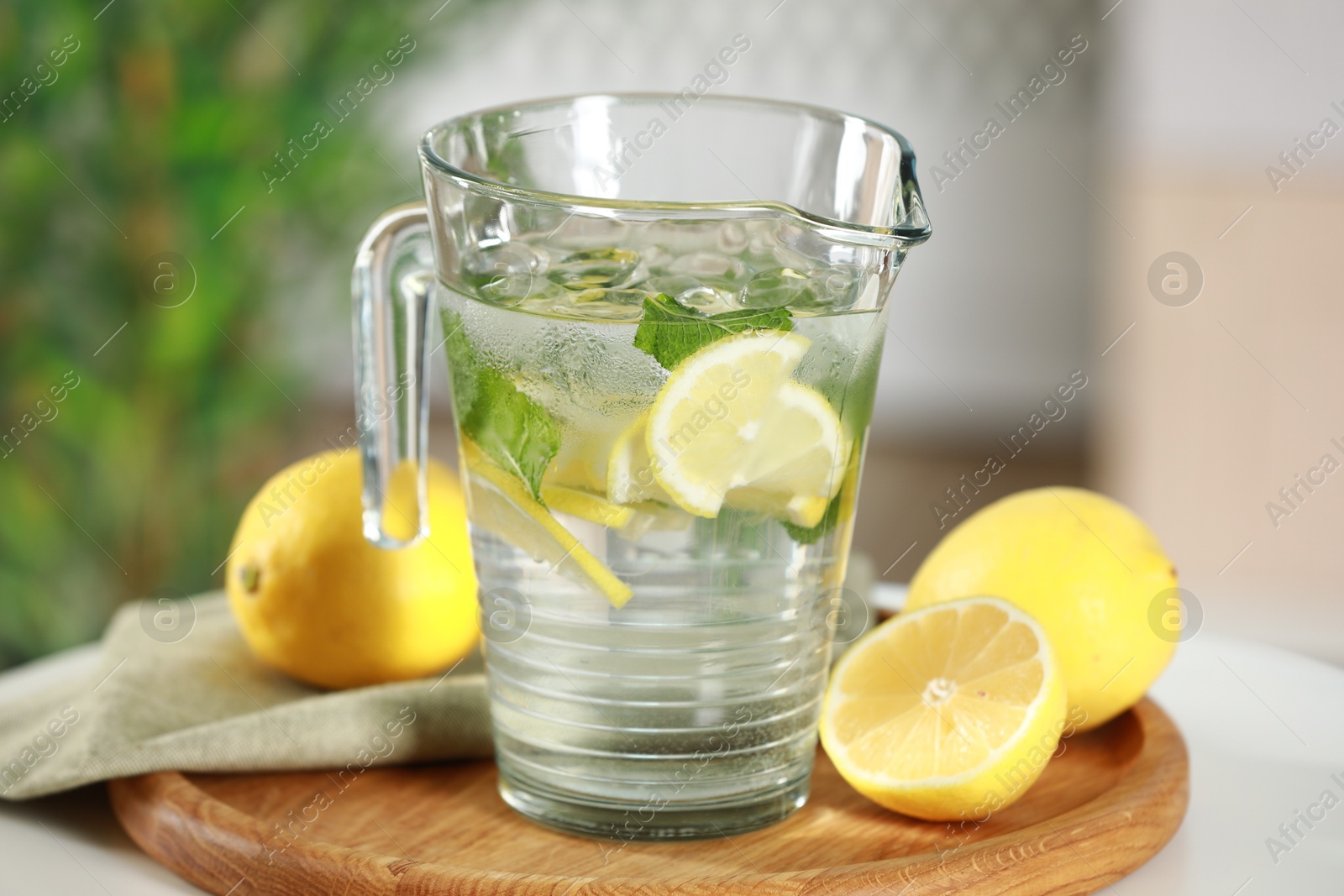 Photo of Refreshing lemonade with mint in jug and citrus fruits on table, closeup