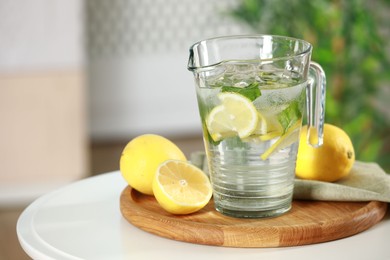 Photo of Refreshing lemonade with mint in jug and citrus fruits on white table. Space for text