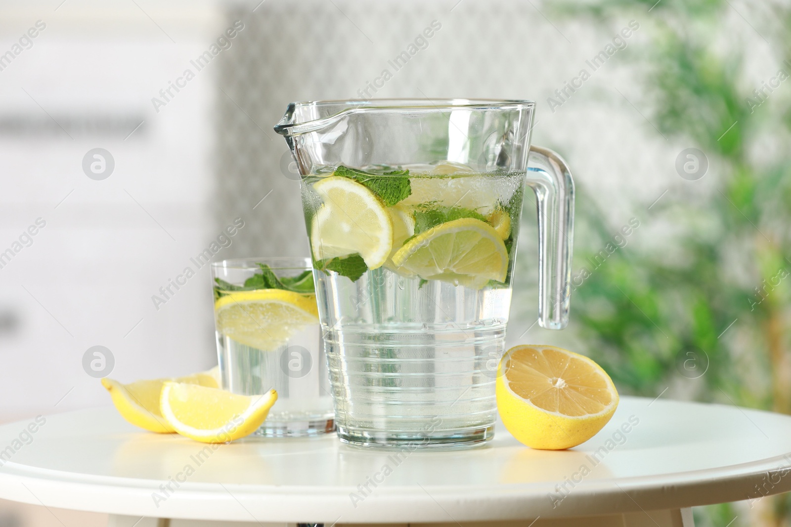 Photo of Refreshing lemonade with mint in jug and glass on white table