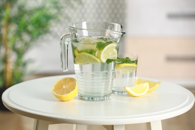 Refreshing lemonade with mint in jug and glass on white table