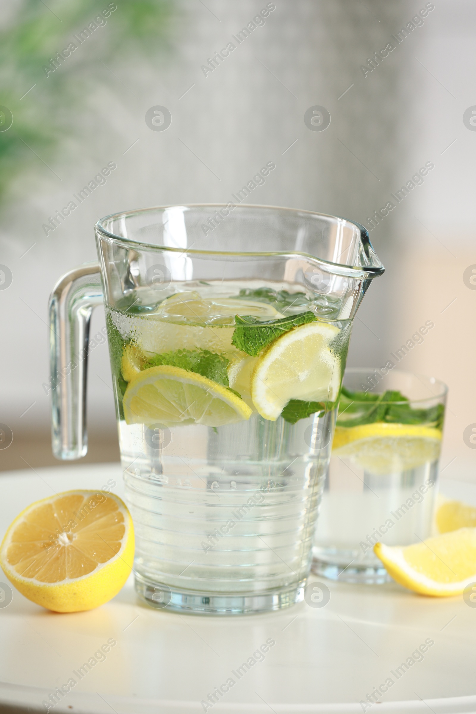 Photo of Refreshing lemonade with mint in jug and glass on white table