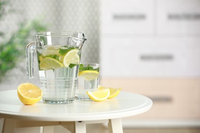 Refreshing lemonade with mint in jug and glass on white table. Space for text