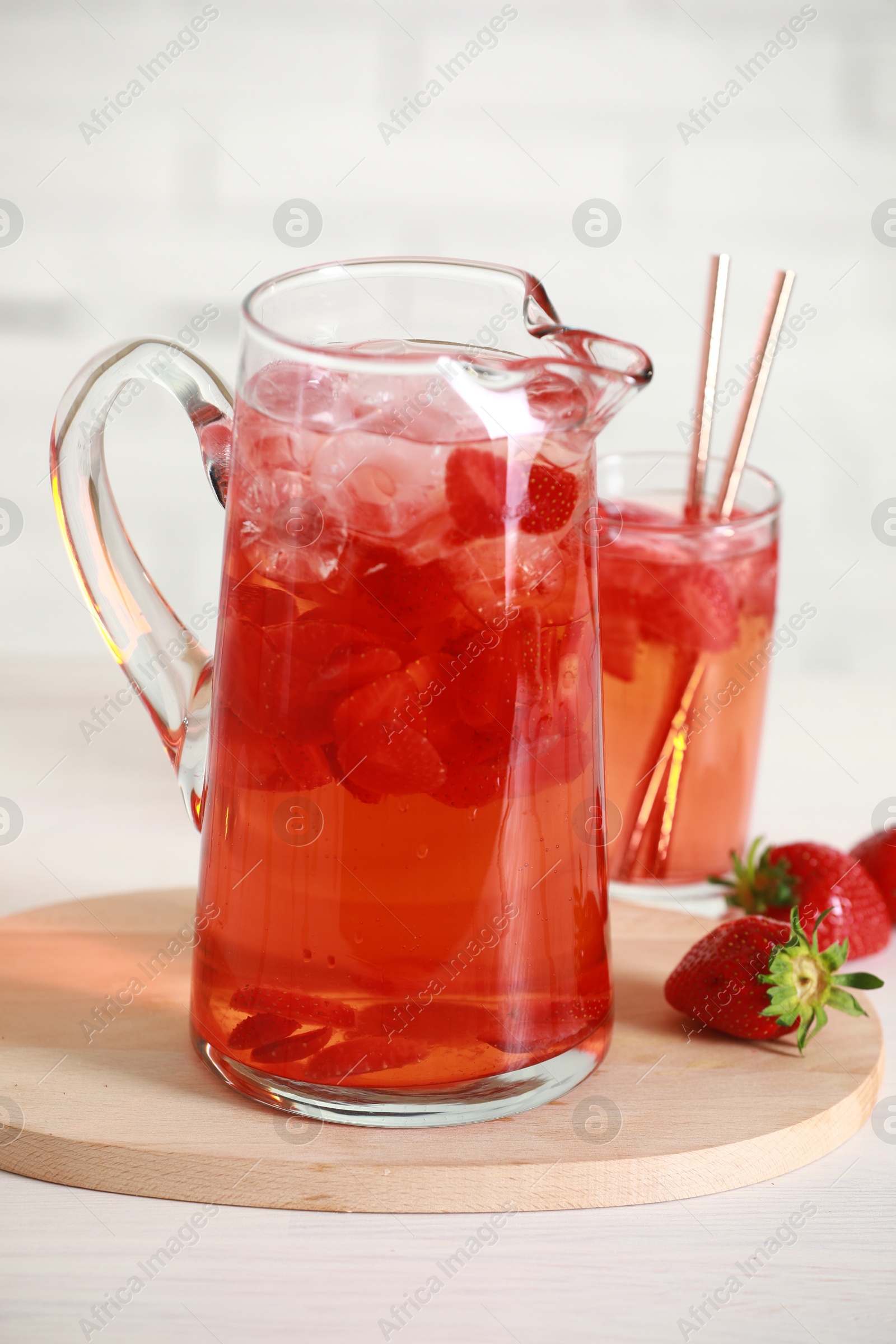 Photo of Tasty strawberry lemonade in jug, glass and berries on white wooden table