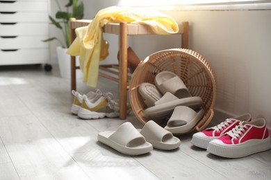 Photo of Basket with slippers for guests and sneakers in entryway at home