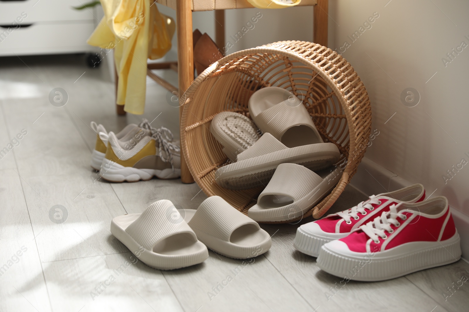 Photo of Basket with slippers for guests and sneakers in entryway at home