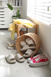 Photo of Basket with slippers for guests and sneakers in entryway at home