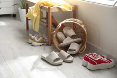 Photo of Basket with slippers for guests and sneakers in entryway at home