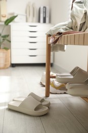 Many pairs of slippers and other shoes in entryway at home