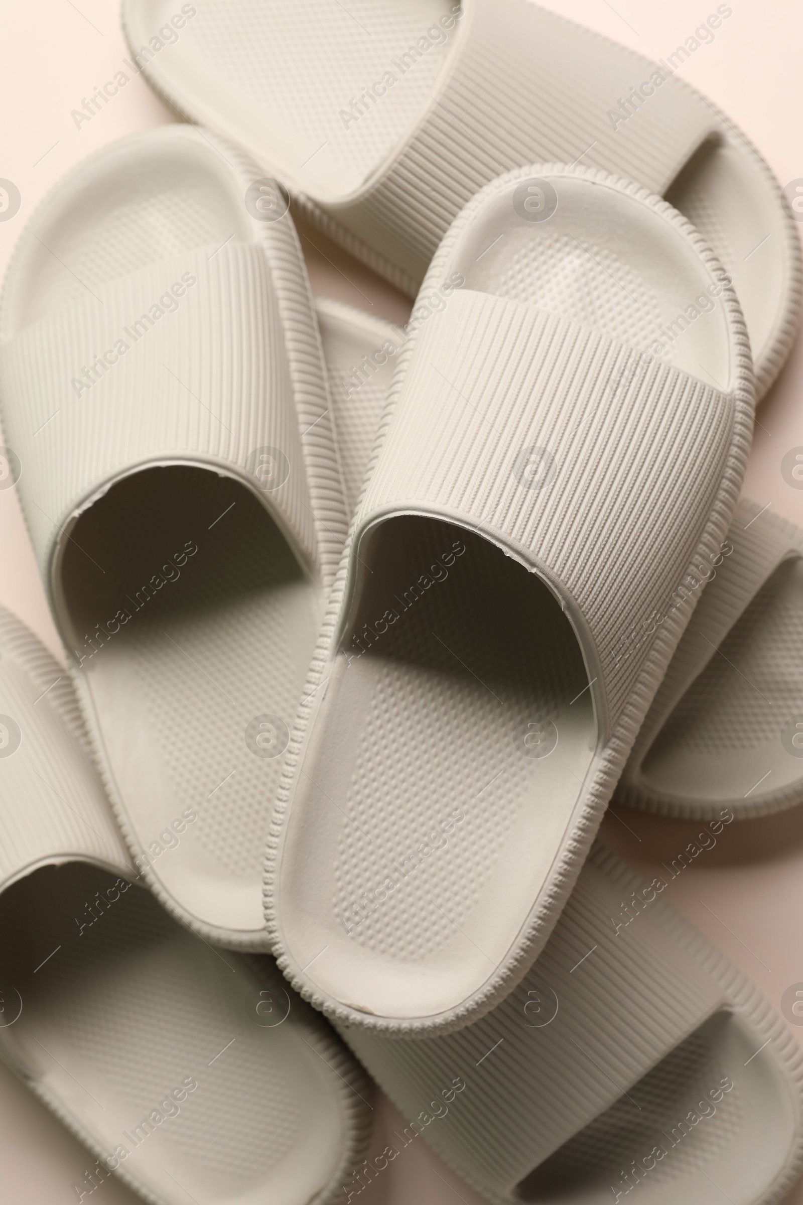 Photo of Pairs of rubber slippers on beige background, top view