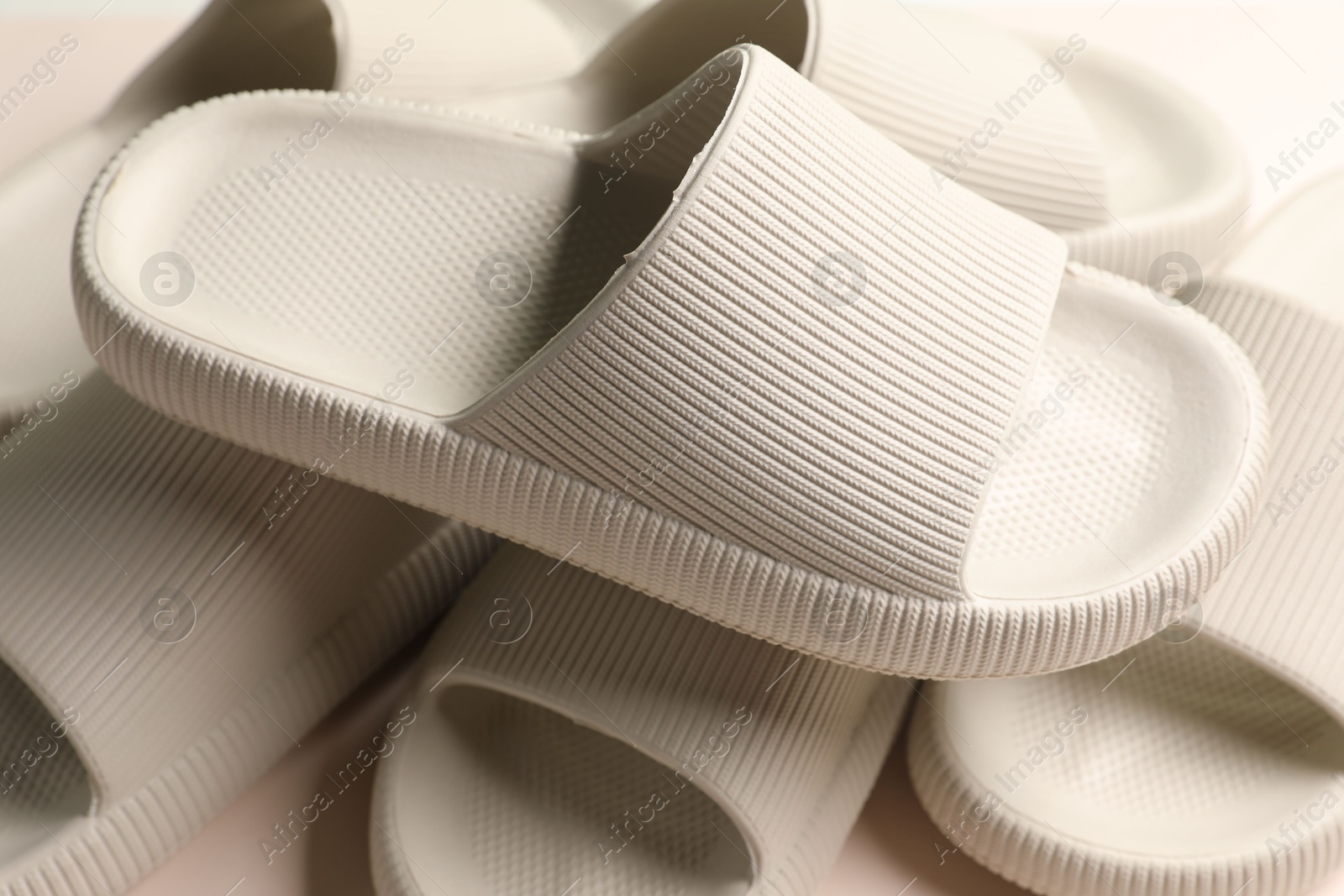 Photo of Pairs of rubber slippers on beige background, closeup