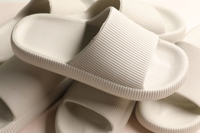 Pairs of rubber slippers on beige background, closeup