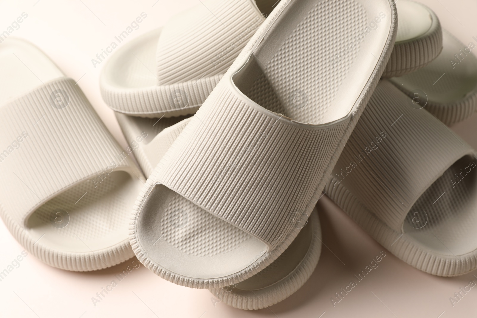 Photo of Pairs of rubber slippers on beige background, closeup