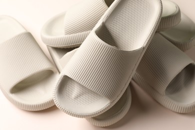 Photo of Pairs of rubber slippers on beige background, closeup