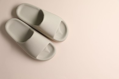 Pair of rubber slippers on beige background, top view. Space for text