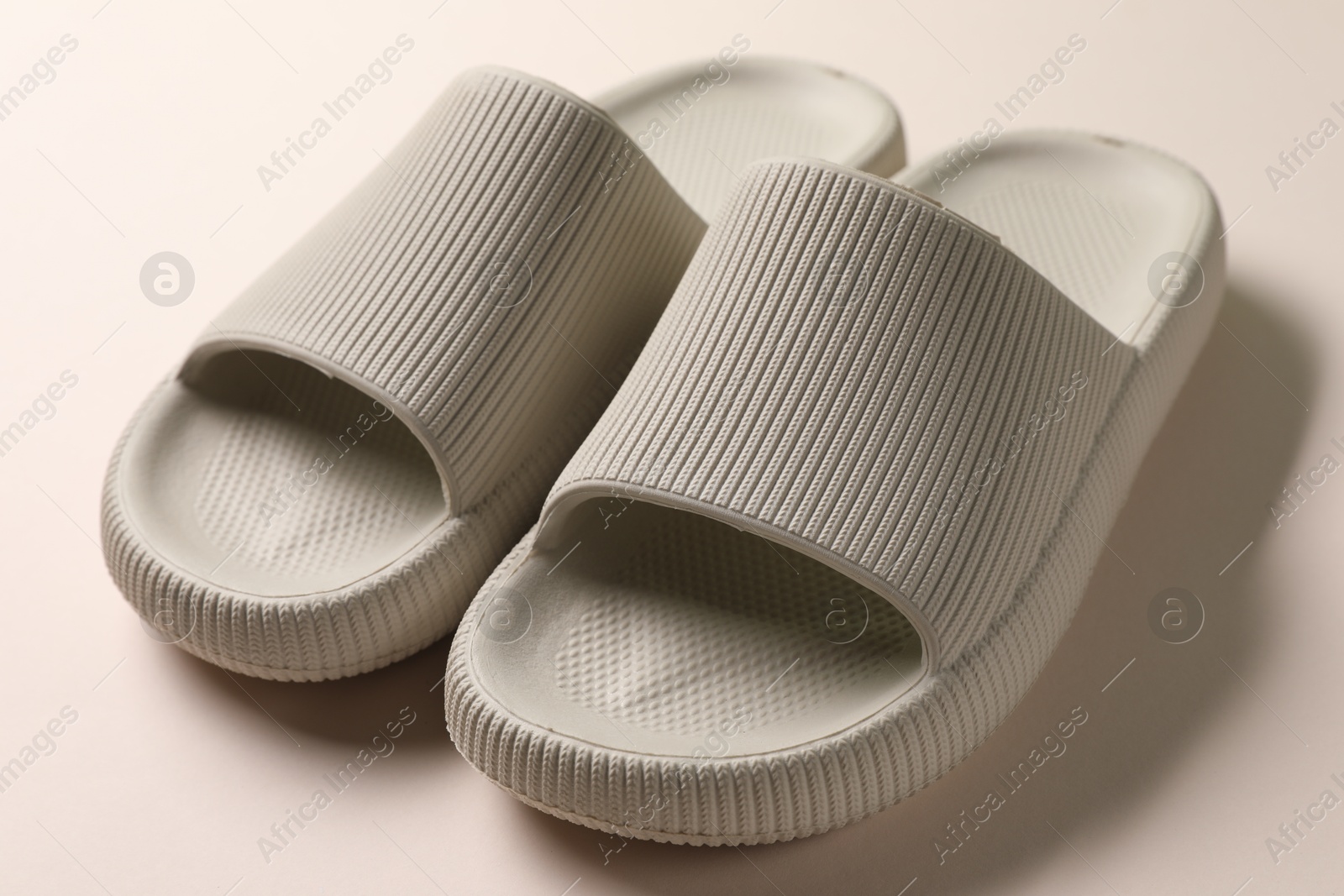 Photo of Pair of rubber slippers on beige background, closeup