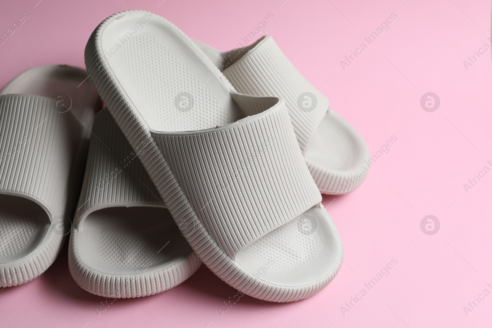 Photo of Pairs of rubber slippers on pink background, closeup