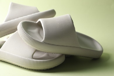 Three white rubber slippers on green background, closeup