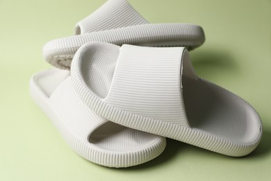 Photo of Three white rubber slippers on green background