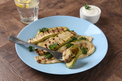 Photo of Eating tasty grilled courgette slices at wooden table