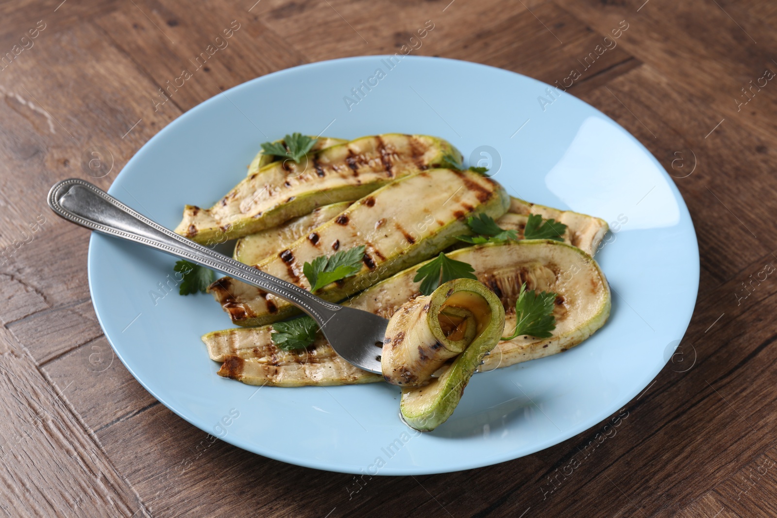 Photo of Eating tasty grilled courgette slices at wooden table