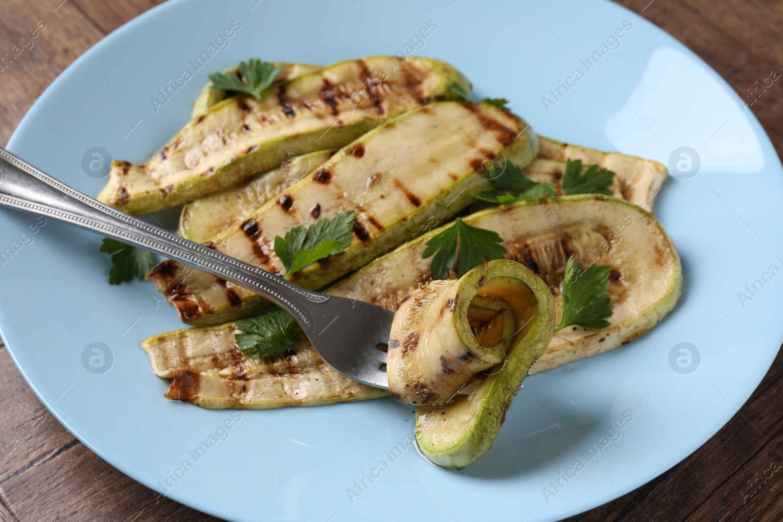 Photo of Eating tasty grilled courgette slices at wooden table