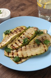 Photo of Tasty grilled courgette slices with parsley on wooden table