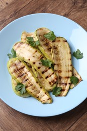 Photo of Tasty grilled courgette slices with parsley on wooden table, top view