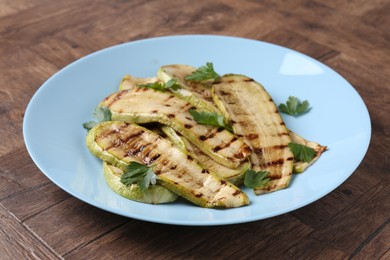 Photo of Tasty grilled courgette slices with parsley on wooden table