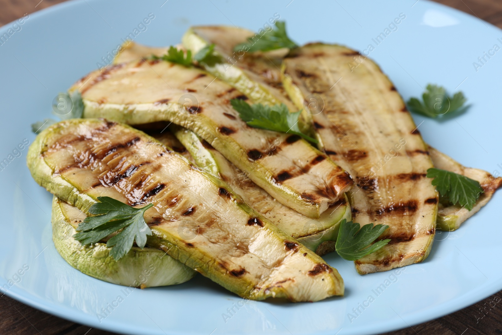 Photo of Tasty grilled courgette slices with parsley on table, closeup