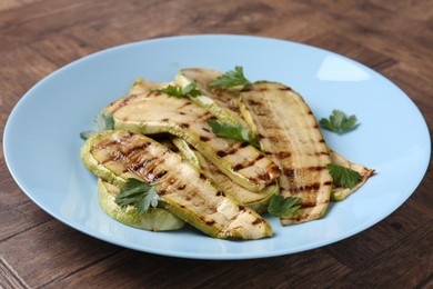 Photo of Tasty grilled courgette slices with parsley on wooden table