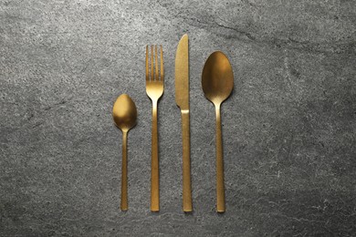 Photo of Stylish golden cutlery on grey table, flat lay