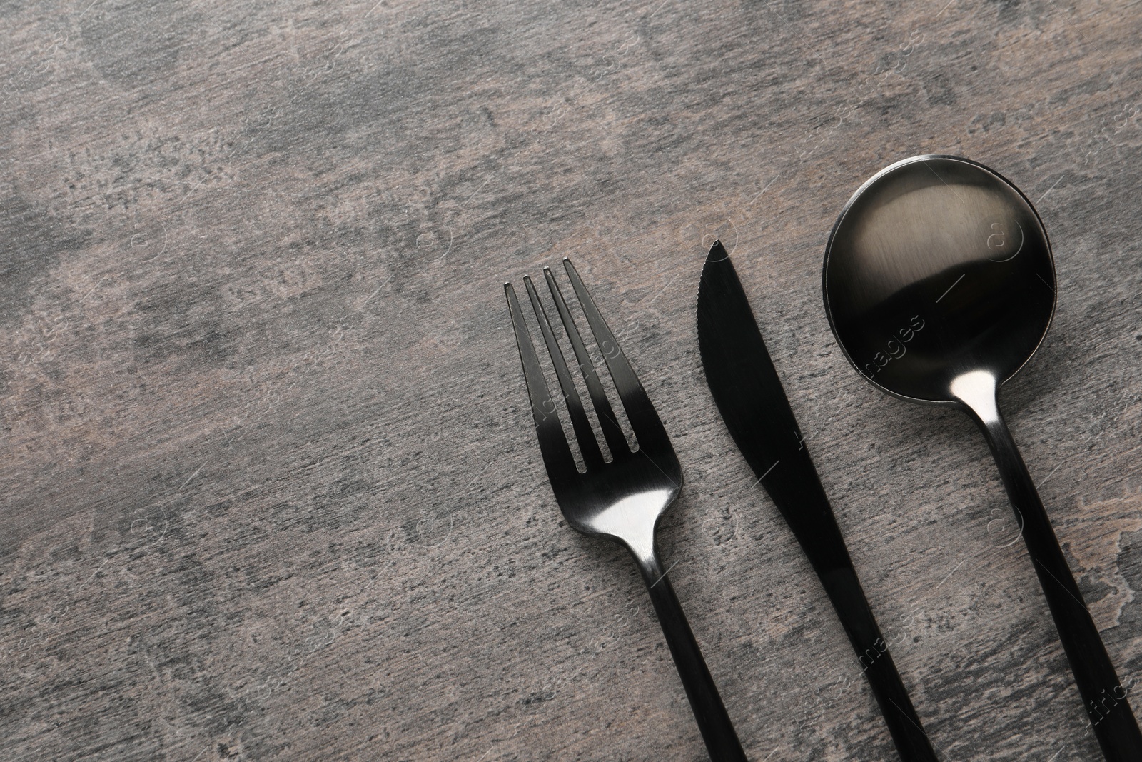 Photo of Stylish cutlery on grey table, flat lay. Space for text