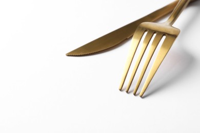 Photo of Stylish golden cutlery on white background, closeup. Space for text