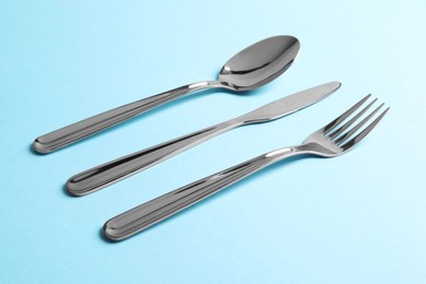 Stylish silver cutlery on light blue background