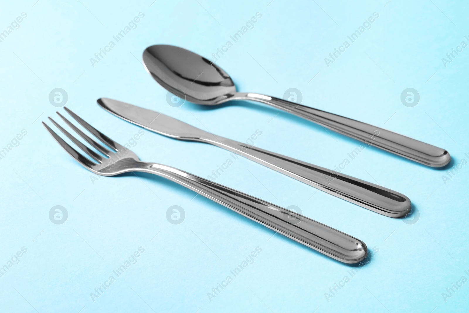 Photo of Stylish silver cutlery on light blue background