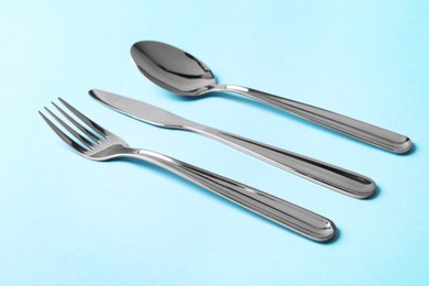 Stylish silver cutlery on light blue background