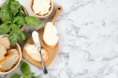 Photo of Pieces of bread with cream cheese and basil served on white marble table, flat lay. Space for text