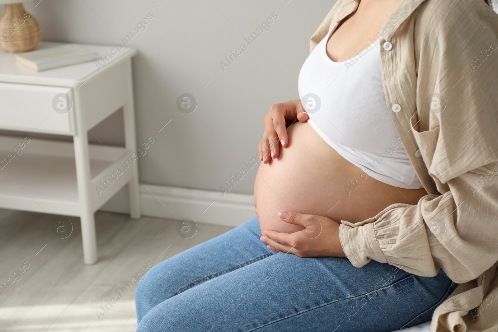 Photo of Beautiful pregnant woman on bed at home, closeup