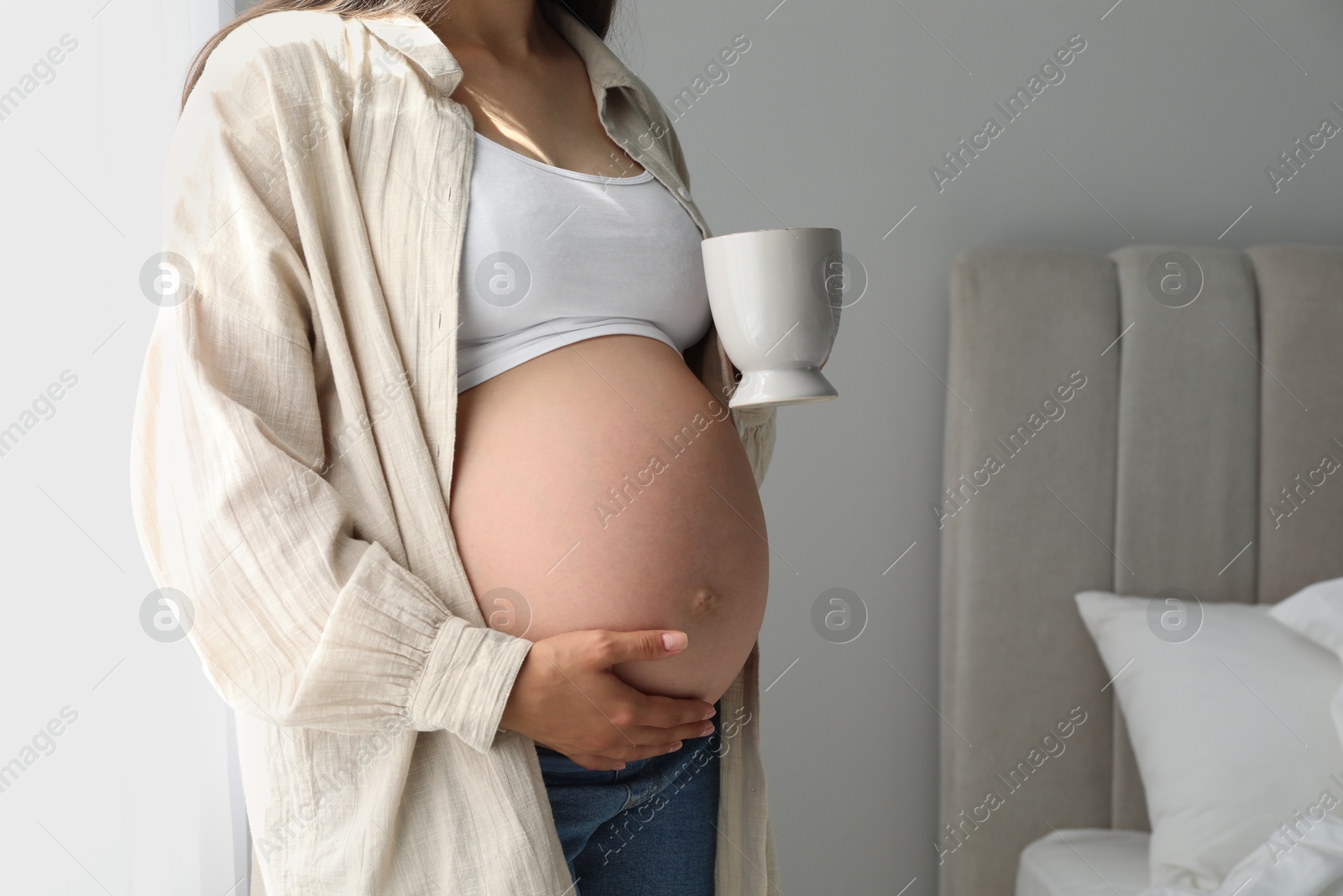 Photo of Pregnant woman with cup at home, closeup