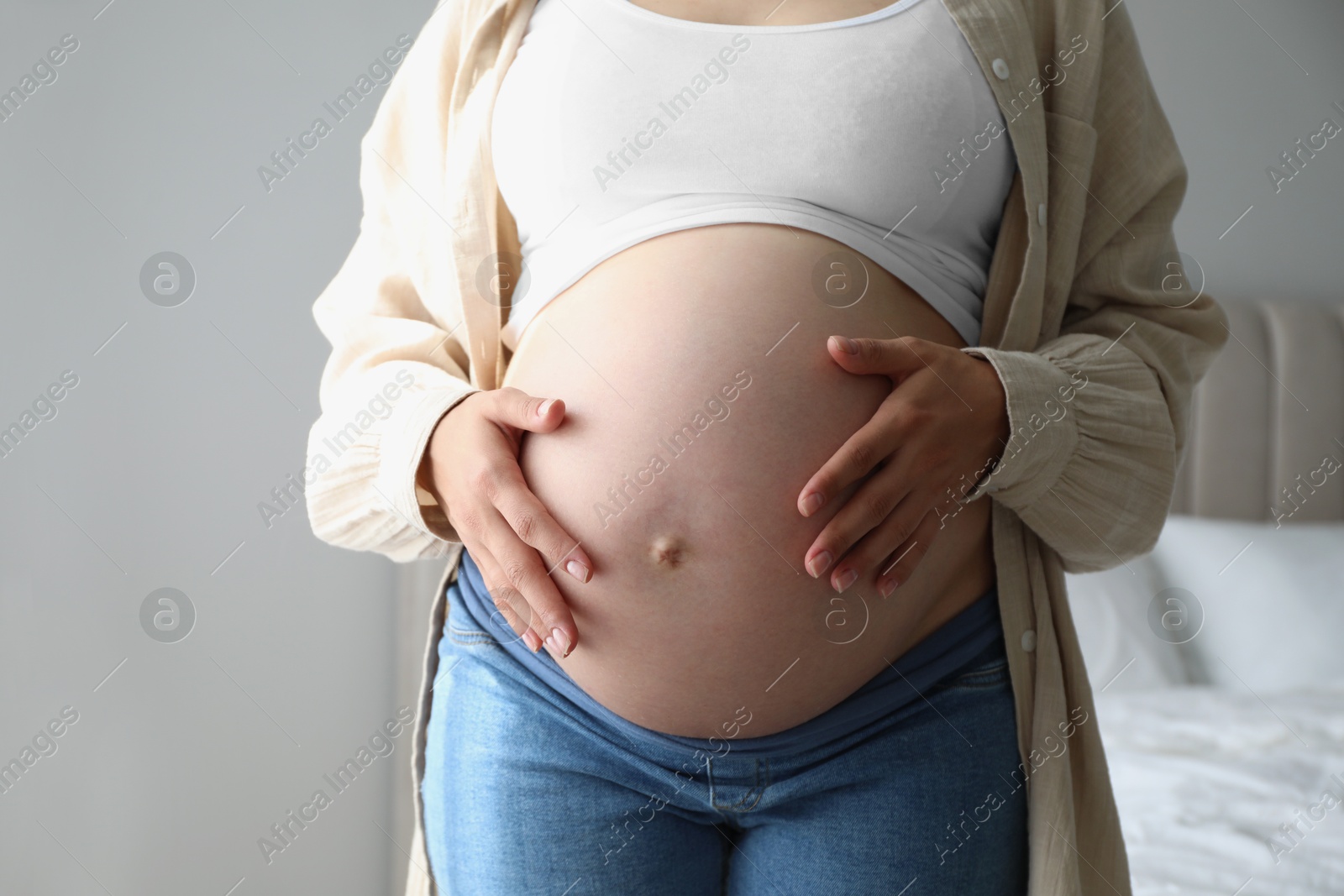 Photo of Pregnant woman in beige shirt at home, closeup