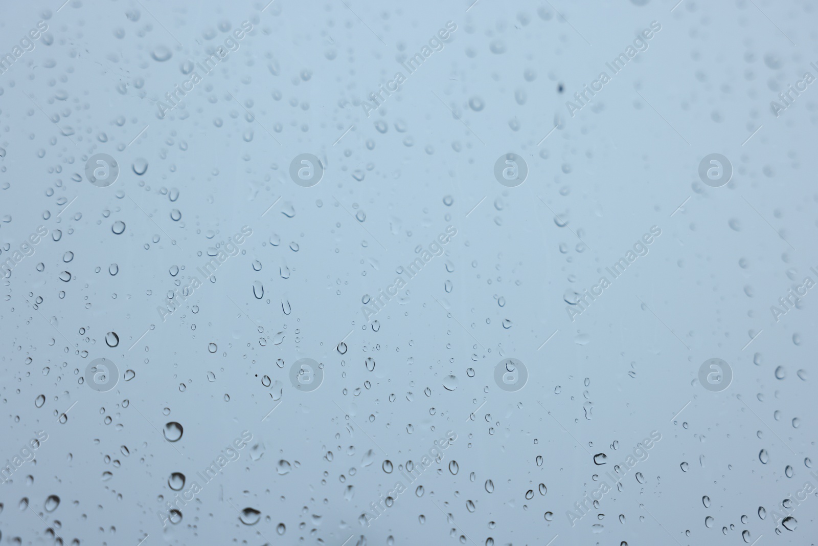 Photo of View on sky through window with water droplets on rainy day, closeup