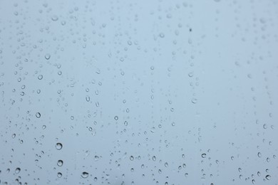 View on sky through window with water droplets on rainy day, closeup