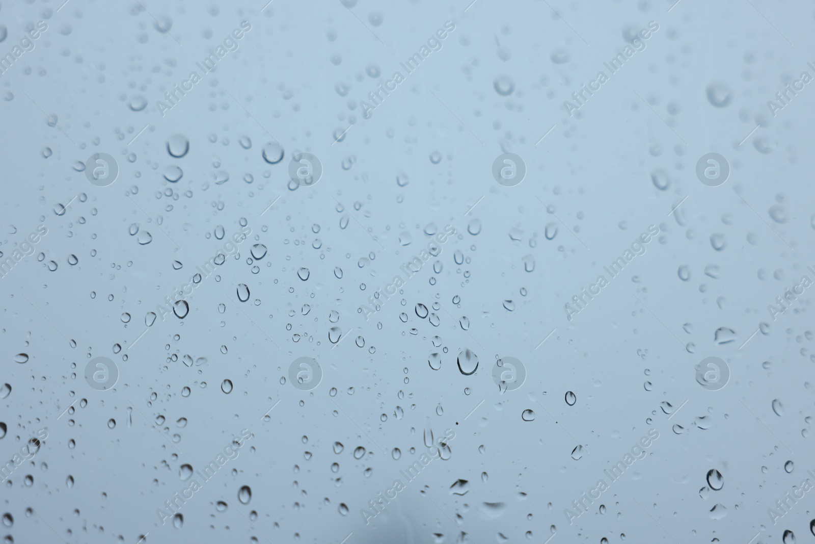 Photo of View on sky through window with water droplets on rainy day, closeup