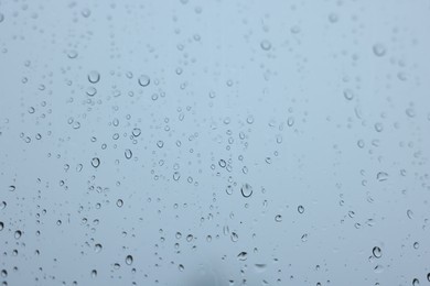 View on sky through window with water droplets on rainy day, closeup